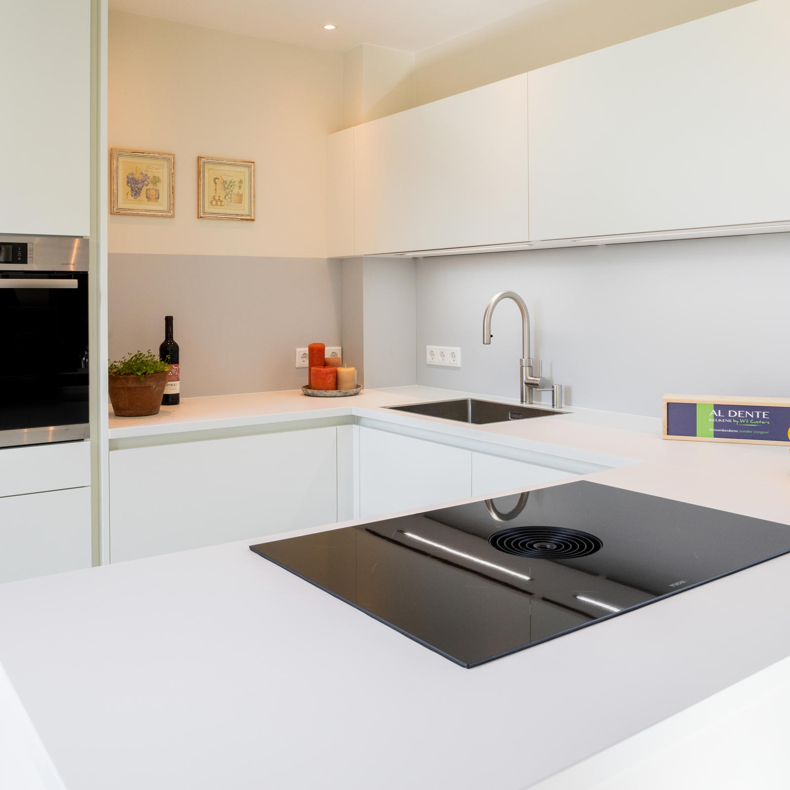 Witte keuken in Maastricht: wit schiereiland met inductiekookplaat met geïntegreerde afzuiging en inbouwoven