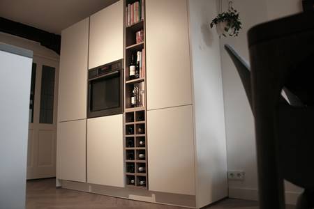 Matwitte keukenwand met houten wijnrek en boekenkast