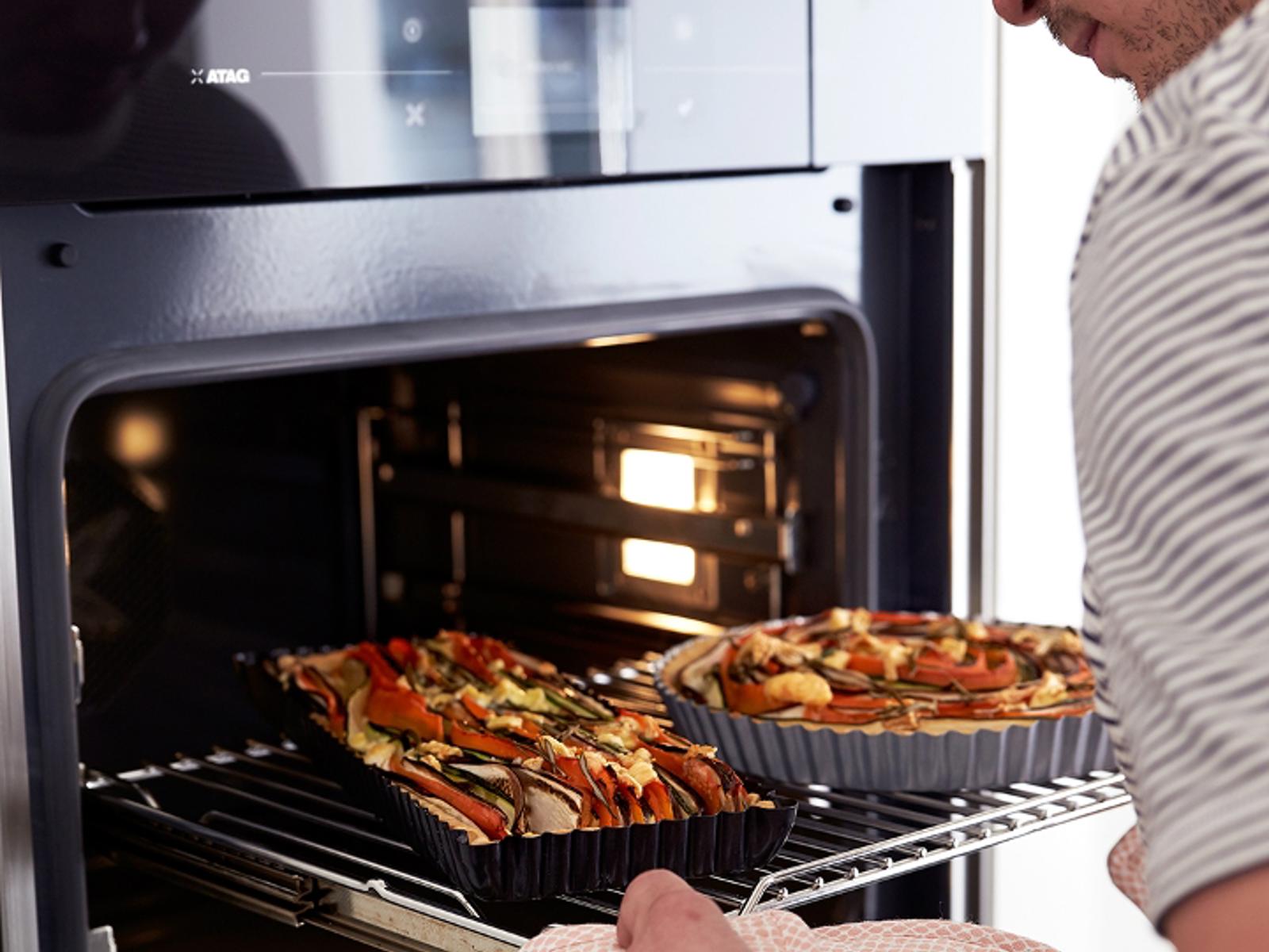 ATAG oven met telescopische geleiders, man schuift een rooster met twee taarten naar buiten