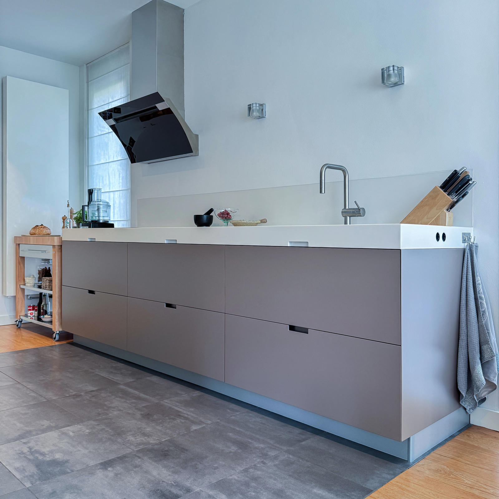 Gerenoveerde keuken in Meerssen: opnieuw gespoten taupe fronten, wit werkblad met RVS kraan en Berbel afzuigkap