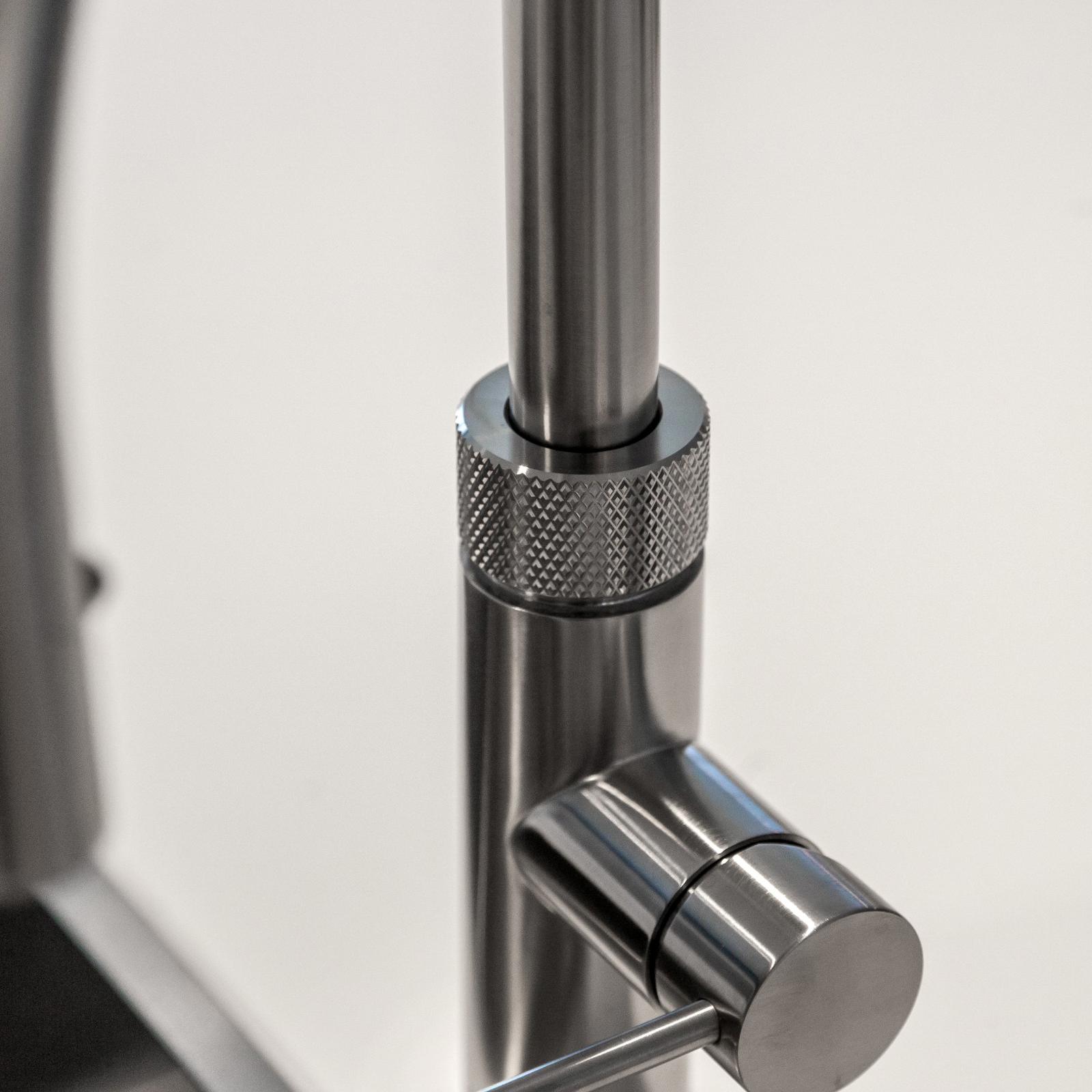 Close-up van een RVS keukenkraan met gekartelde ring en hendel