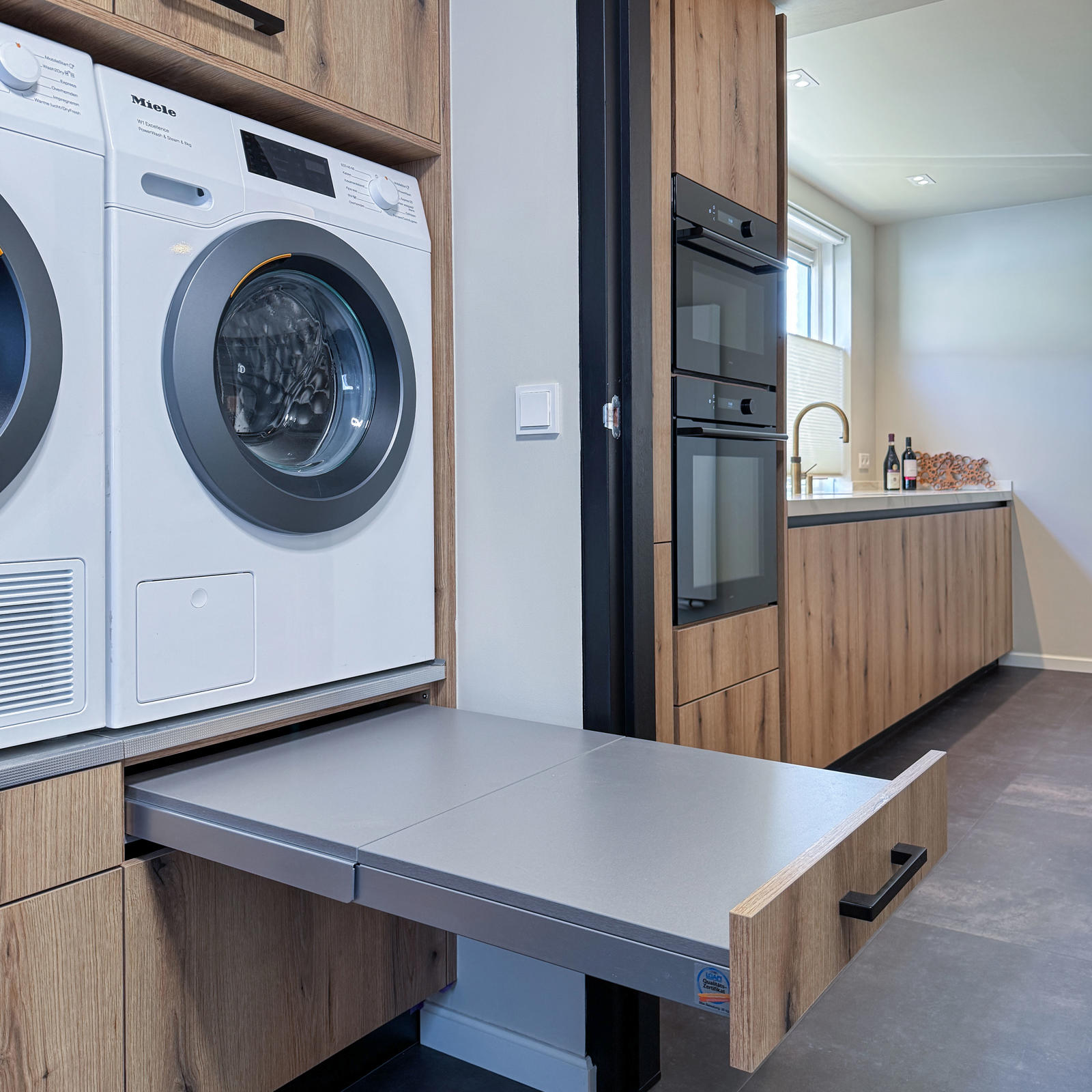 Bijkeuken in Banholt: uittrekbaar werkblad onder de wasmachine om de wasmand op te zetten
