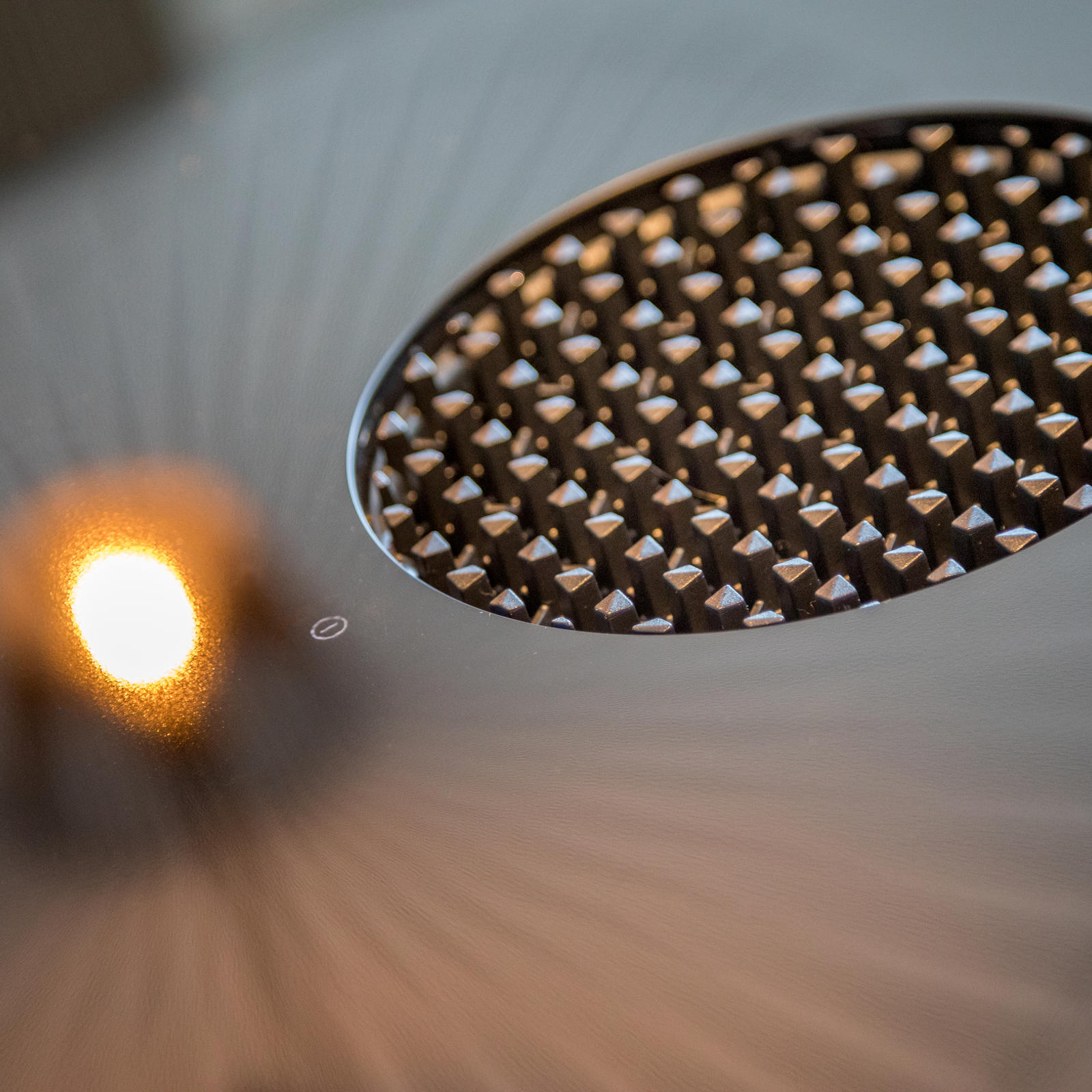 Rond afzuigrooster in de kookplaat met weerspiegeling van een hanglamp