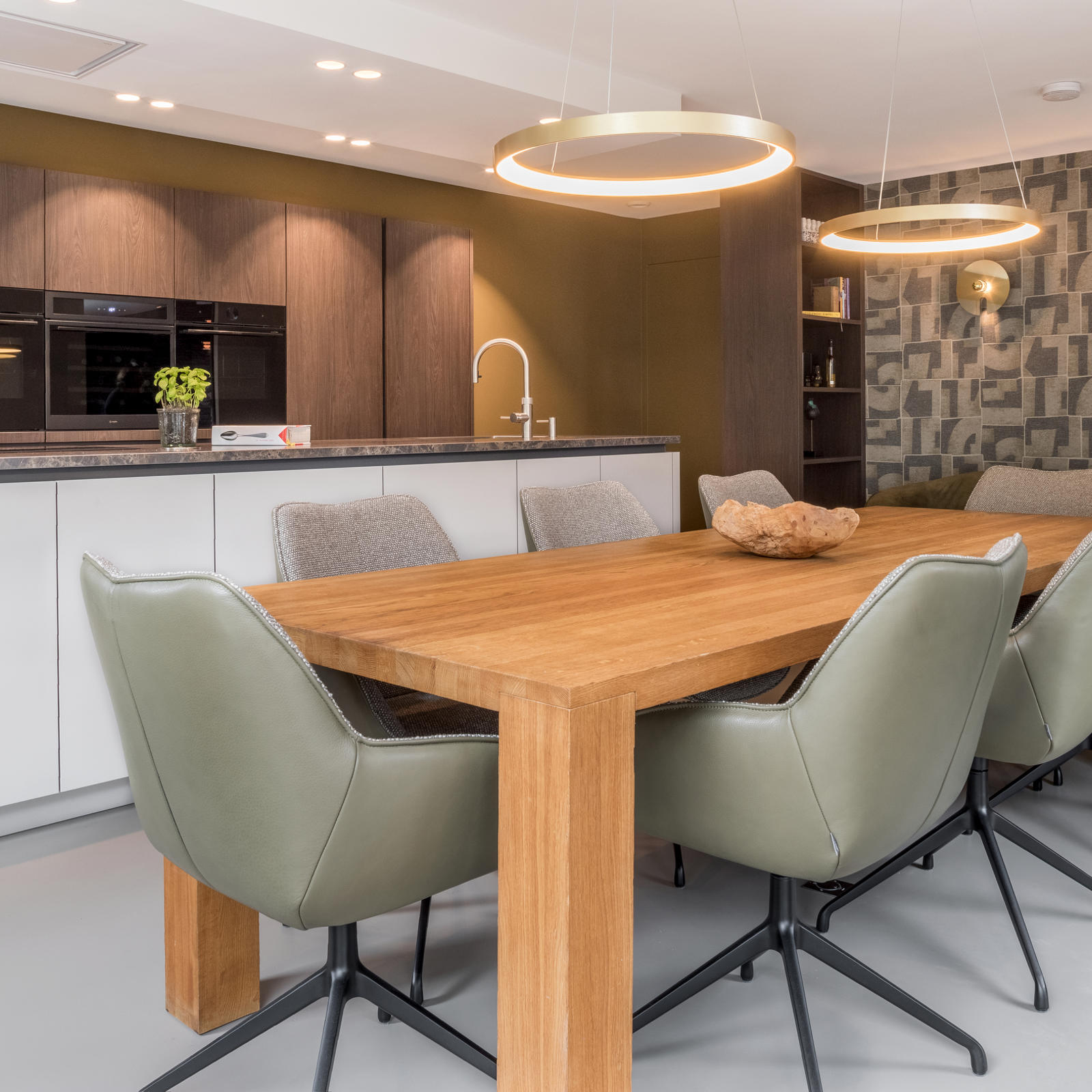 Hoge kasten in houtlook in Maastricht-West: wit keukeneiland met houten eettafel en groene stoelen