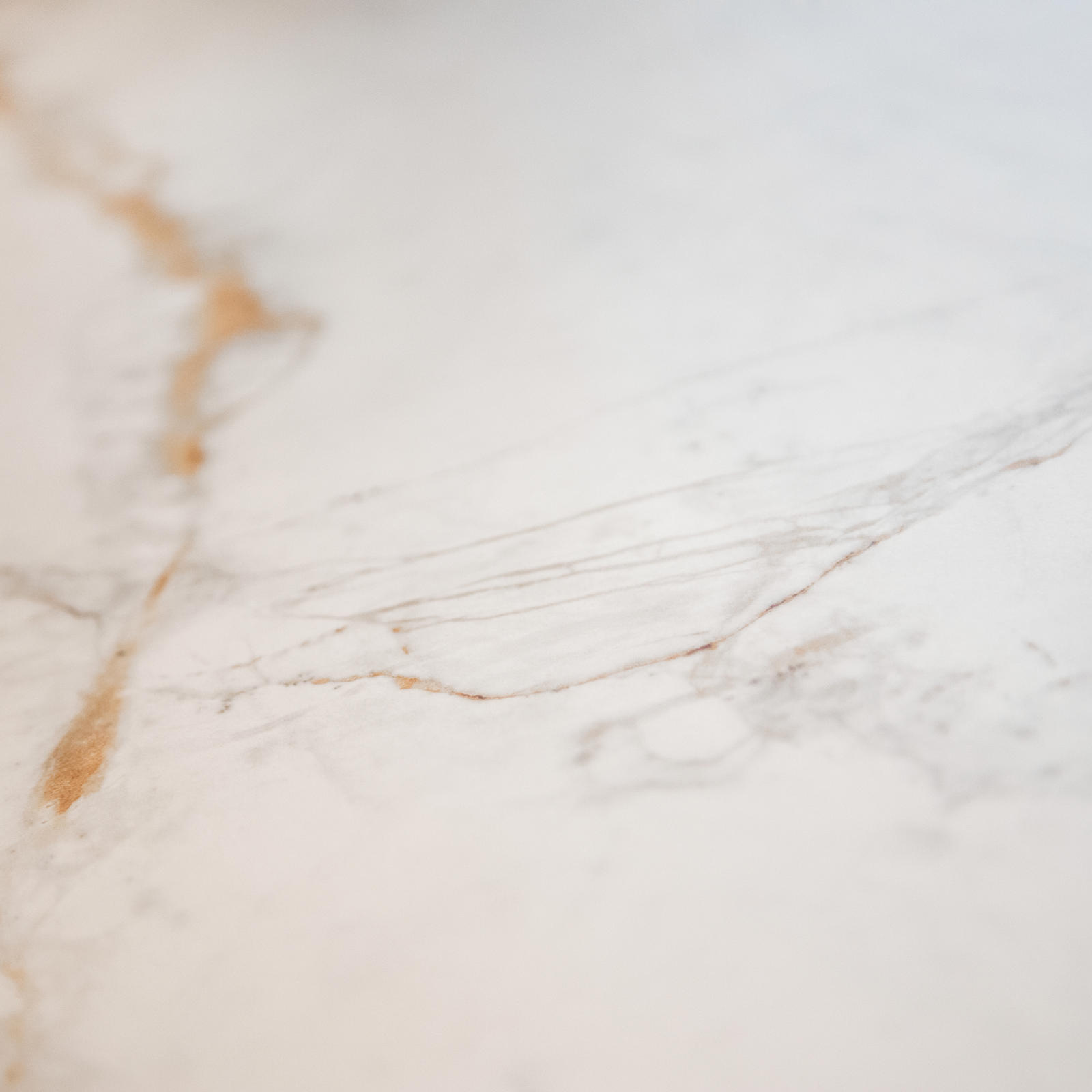 Close-up van keramisch werkblad in wit met marmerlook en goudkleurige aders
