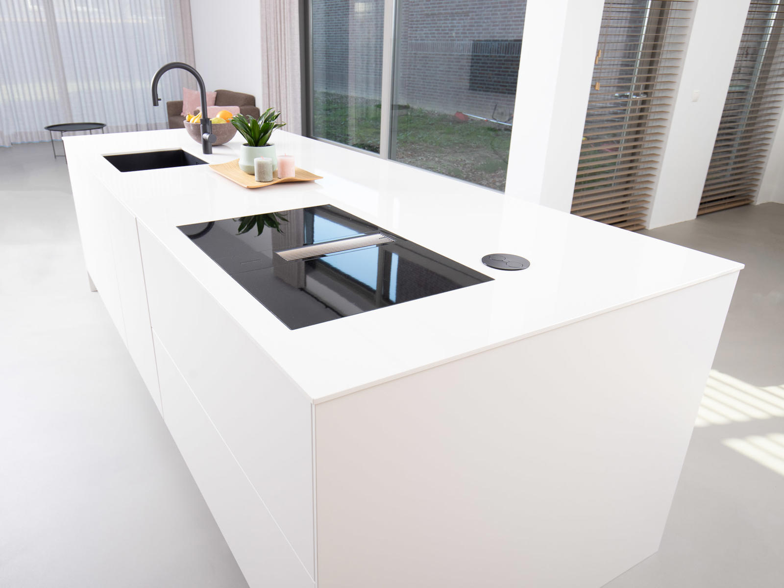 Strakke greeploze keuken in Eijsden: wit kookeiland met inductiekookplaat met afzuiging en spoelbak