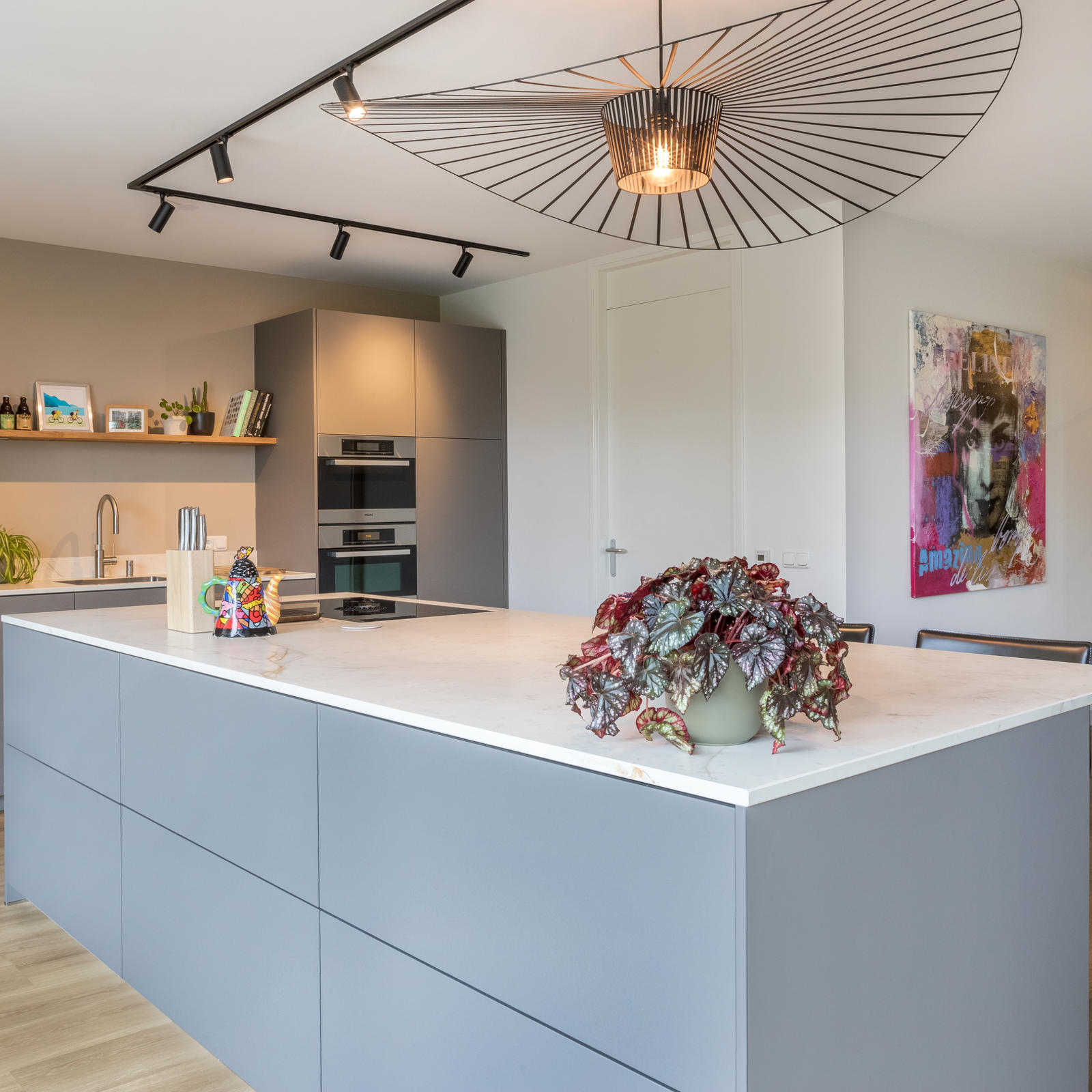 Keuken met kookeiland in Meerssen: taupe greeploos kookeiland met keramisch werkblad en grote designhanglamp