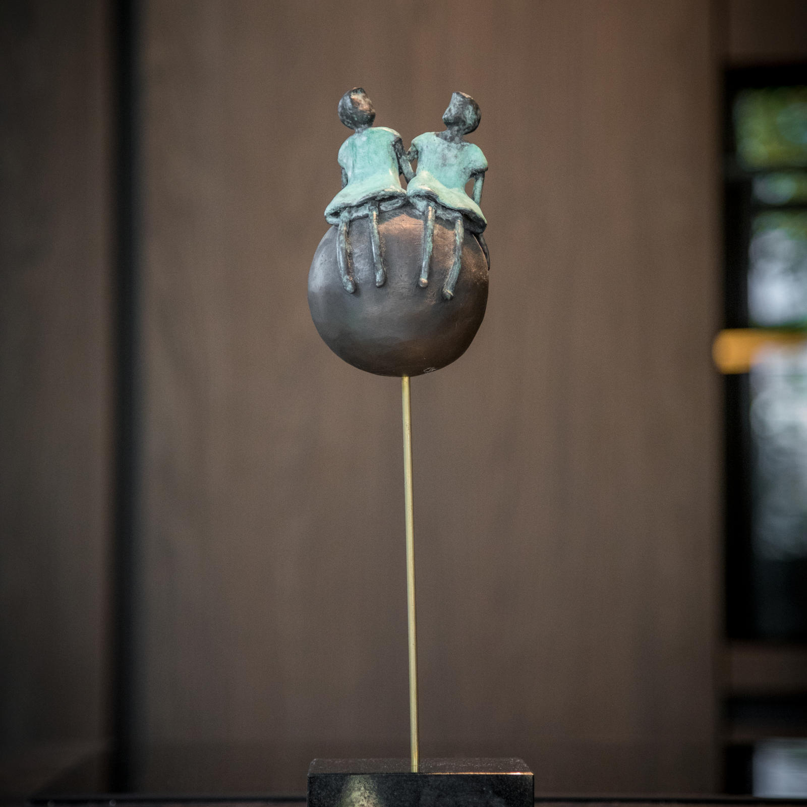 Bronzen beeldje van twee figuren op een bol als decoratie op het werkblad