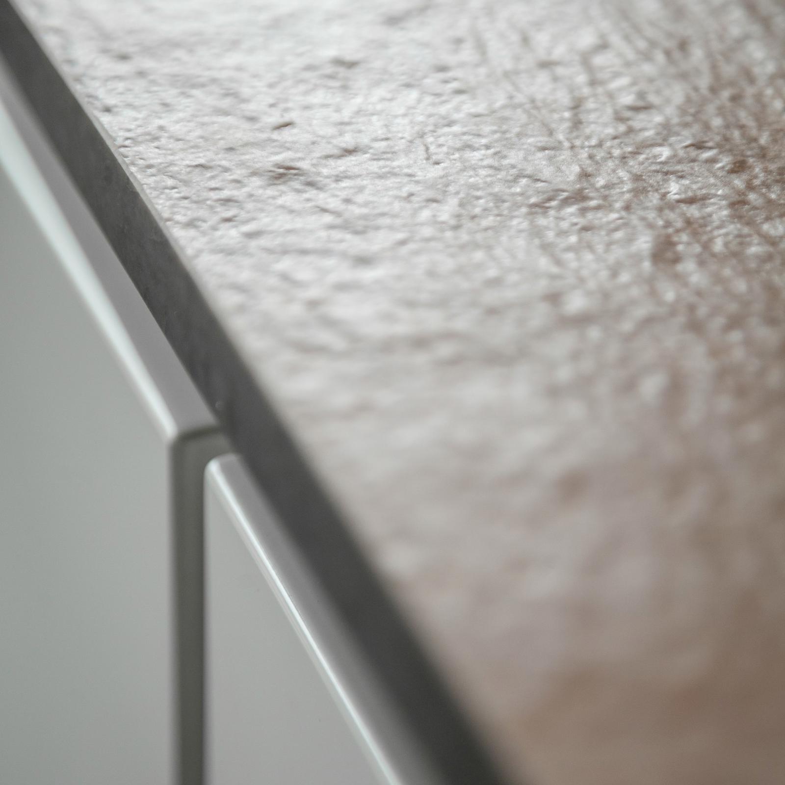 Detail van een gestructureerd grijs werkblad boven witte greeploze lades